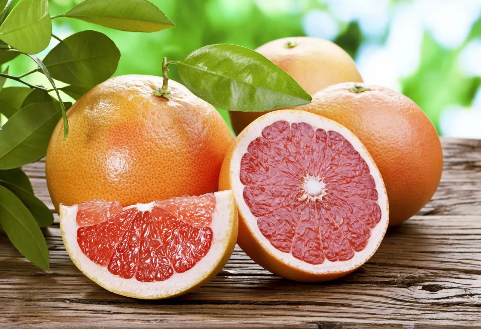 Fresh citrus fruits with green leaves on a wooden table